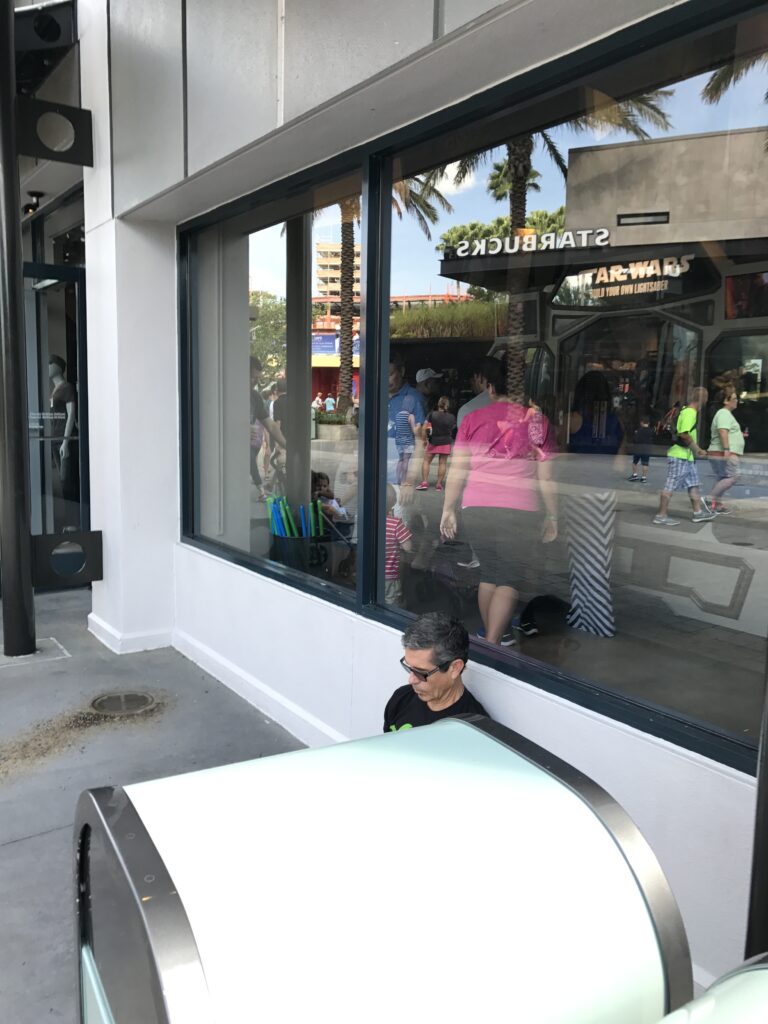 man sitting next to Disney shop