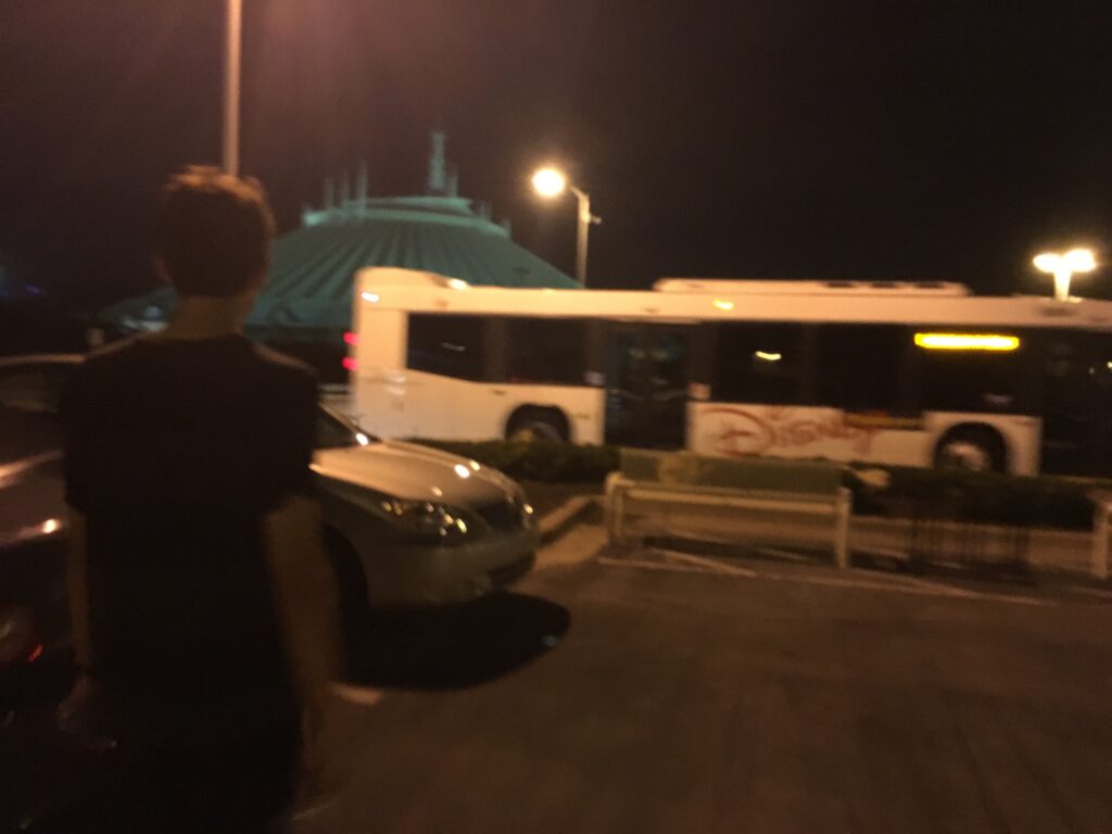 person walking towards Disney bus at night