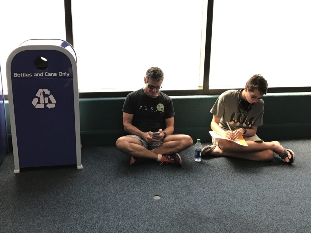 two people sitting on floor next to Disney trash can
